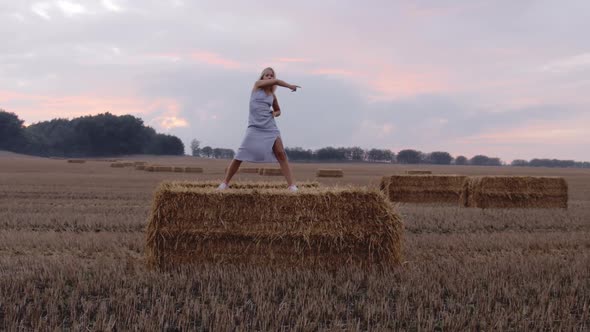 A Pretty Blonde Female Dancing on Top Of a Haystack