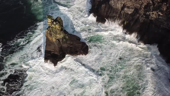 Rock next to the cliffs of Moher, Ireland, white foam of the big waves that crash. drone aerial clip