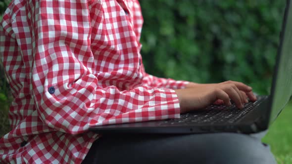 Closeup of Small Female Hands Working on a Laptop Keyboard Girl Sitting on the Grass Outside in the