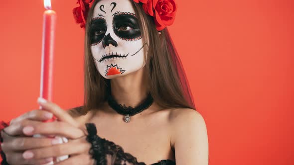 Day of Dead Female with Skull Makeup Moving Candle in a Circle and Sharply Extinguishing It Posing