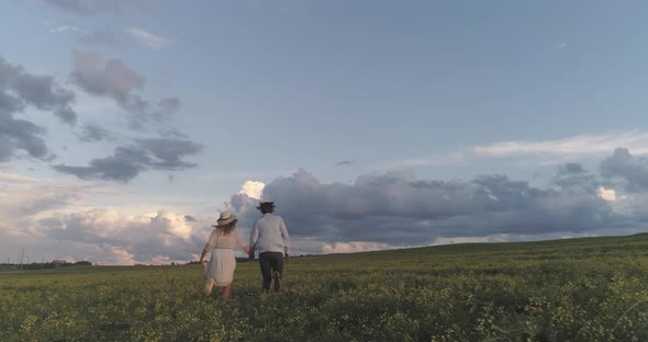 Back View Young Couple Relaxing in Nature a Man and a Woman are Running Through a Field of Rapeseed