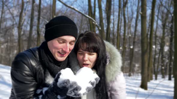 Happy Couple Blows Snow Snowflakes. Slow Motion Winter Sunny Day