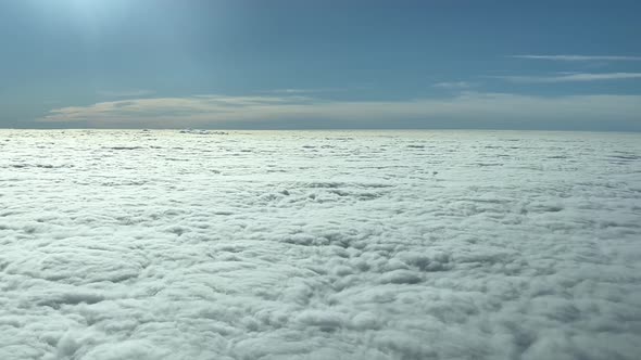 Cumulus dense clouds with sunny clear sky from above. Airplane pov shot. Wide cloudscape view from u