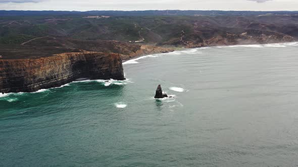Praia da Arrifana cliffs with a crumbled rock in west Portugal Atlantic coastline, Aerial approach s