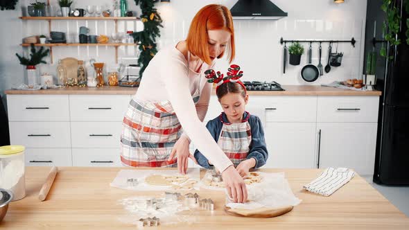 Zoom Out Shot of Happy Mother and Little Daughter Wearing Aprons Making Christmas Gingerbread