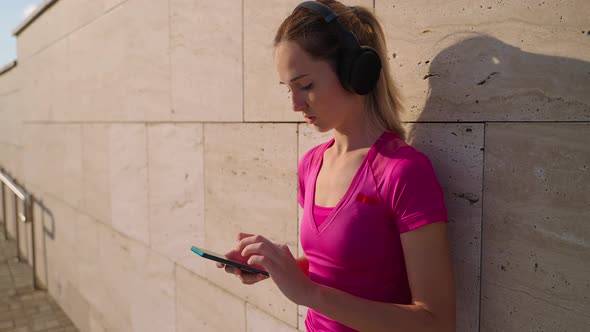 Sportswoman Having a Break with Music and Mobile