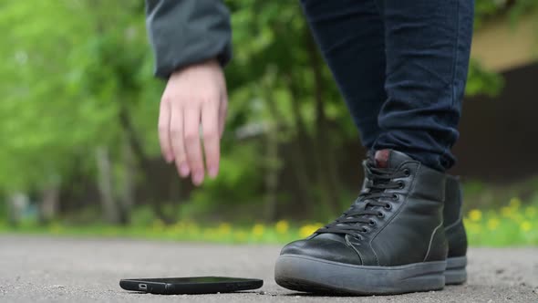 The girl finds a smartphone on the street and picks it up from the asphalt