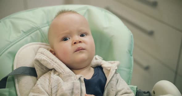 Sensible Infant Briskly Eating Puree From a Spoon By Mother in a Chair