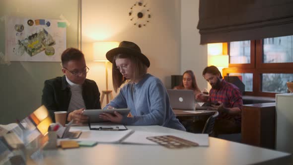 Two Stylish Diverse People Are Sitting At The Table While Energetically Discussing the Project