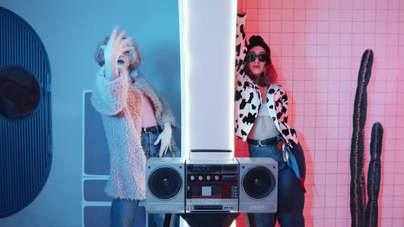 Two Stylish Women Dancing Vogue in Rooms with Blue and Pink Lights