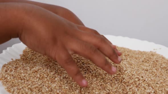 Micro shot of picking sesame seeds with both hands from a  plate