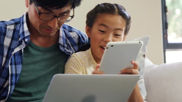 Family using digital tablet and laptop in living room 4k