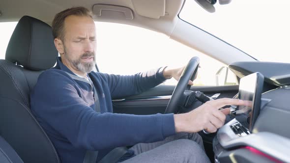 A Middleaged Handsome Caucasian Man Works on the Touchscreen System on the Dashboard in a Car