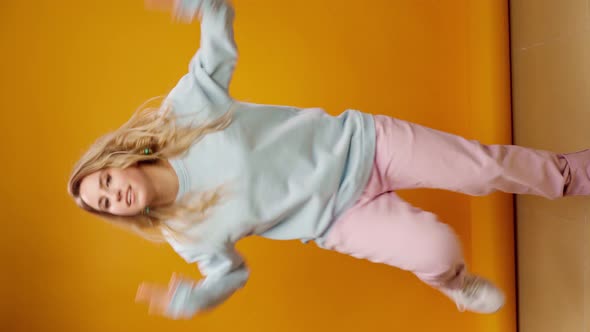 Vertical Video of a Woman Dancer Moving Against Yellow Background in Studio