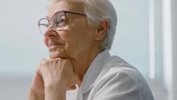 Smiling senior woman doctor with elegant glasses leans