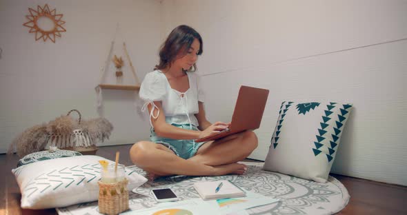 Woman Works From Home She Sits in Her House Room and Types on Keyboard of Her Laptop Computer