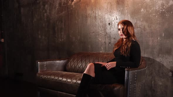 Alone Sensual Redhead Woman Is Relaxing on a Luxury Couch in a Hall