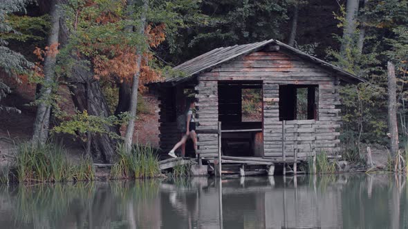 Young Woman Tourist Walks in the Wooden Little House Near the Lake