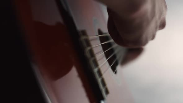 Male Musician Plays Guitar Strings Using Pick Closeup of Hands