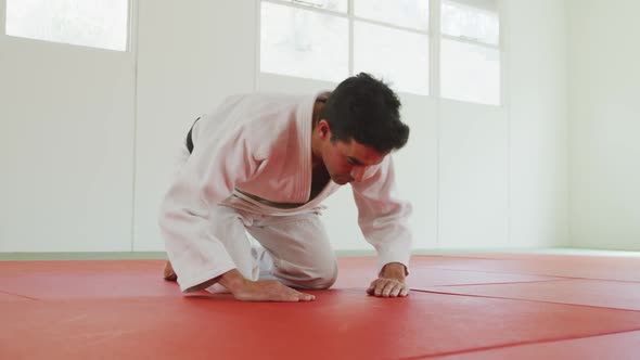 Kneeling judoka saluting on the judo mat