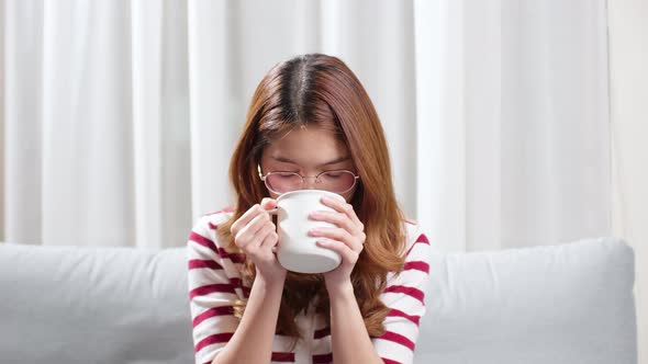 Asian young woman on a cold day drinking a hot cup of tea to relax.