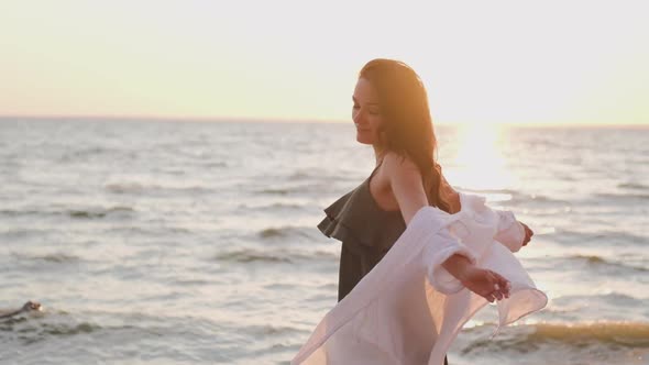 Beautiful Girl Dancing on the Beach in a White Shirt. Free Girl with Long Hair in a White Shirt