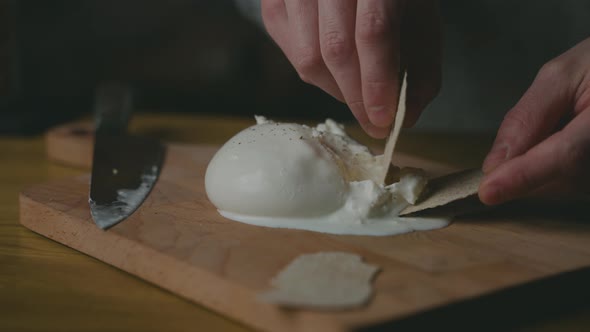 Scooping soft and creamy artisanal Burrata cheese onto a biscuit