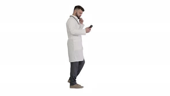 Male Doctor in White Medical Uniform Walking and Using Smartphone on White Background