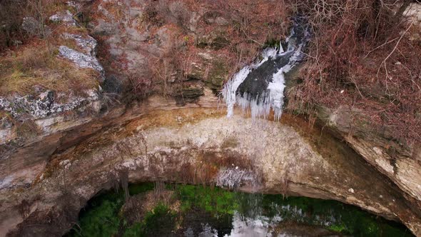 Small Waterfall with Portions of Ice on Wet Rocks and Greenery