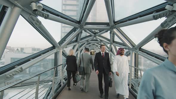 Business People Going To Work Along Indoor Glass Walkway