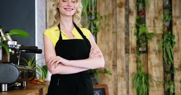 Portrait of waitress standing with arms crossed at counter