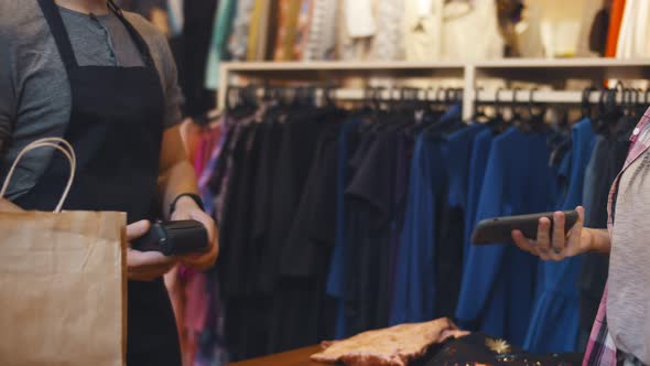 Close Up of Customer in Clothing Store Making Contactless Payment with App on Mobile Phone