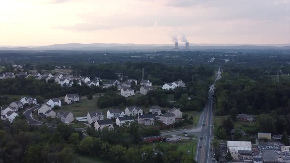 Sun setting over housing development power plant in background