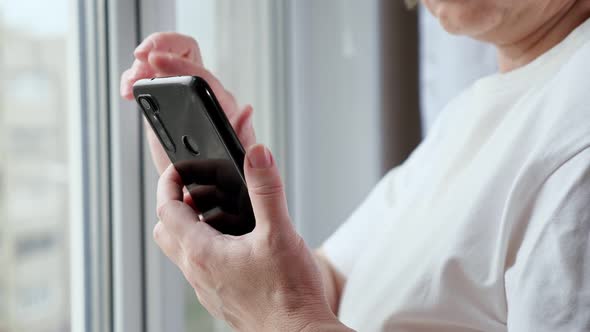 Senior Woman in White Tshirt Uses Modern Smartphone