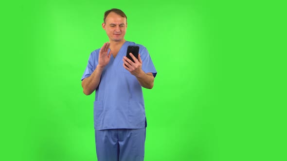 Smiling Man Talking for Video Chat Using Mobile Phone and Rejoice on Green Screen.