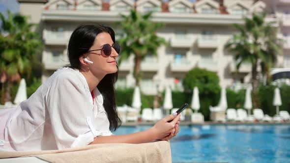 Smiling Girl Sunbathing Listening Music Relaxing Near Swimming Pool at Luxury Resort