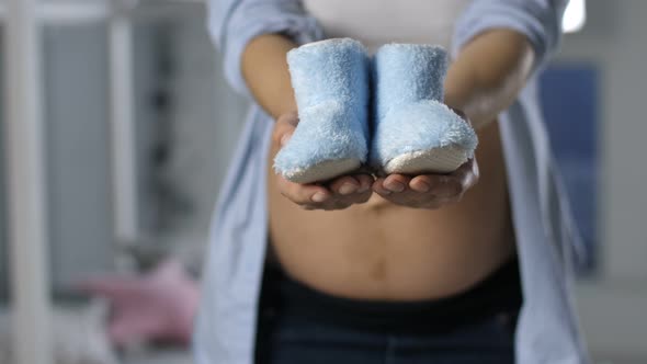  Pregnant Female Hands Showing Baby Shoes