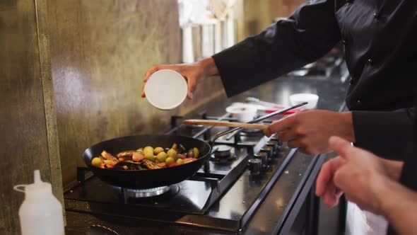 Mixed race male chef preparing a dish and smiling in a kitchen