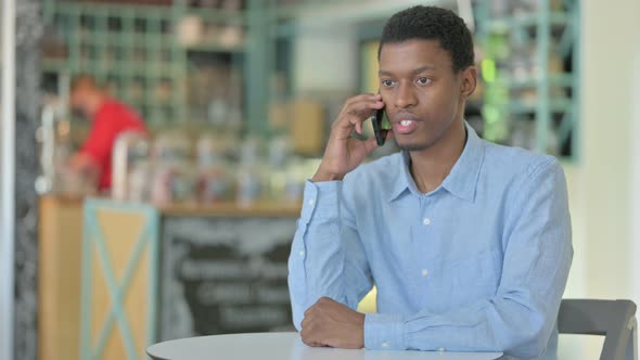 African Businessman Talking on Smartphone in Cafe 