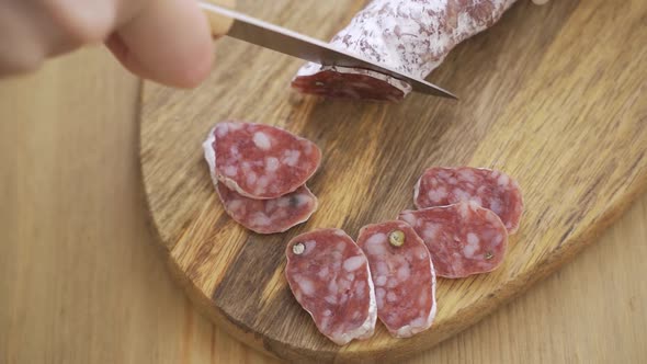 Chef Slices Spanish Traditional Homemade Choriso Sausage Into Pieces on a Wooden Cutting Board