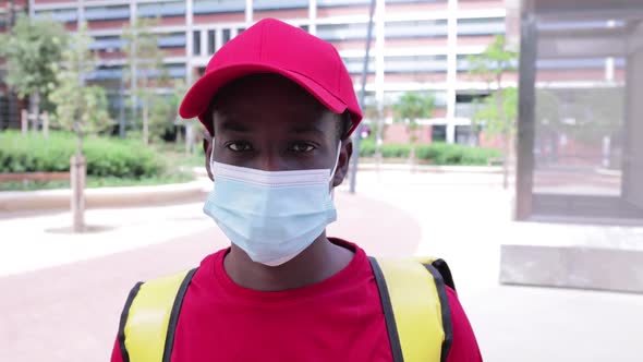 Delivery Man in Red Uniform Taking Off Protective Face Mask and Smiling