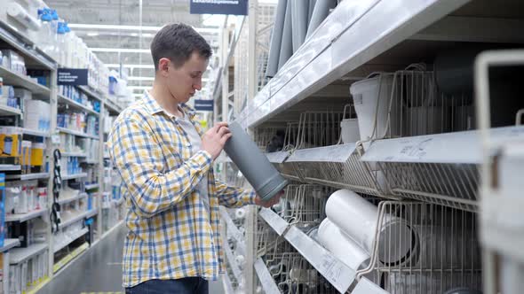 Young Man Compares Sewer Pipes in a Specialty Store