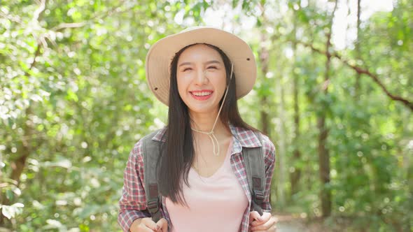 Portrait of Asian beautiful woman backpacker traveling alone in forest.