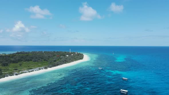 Island location surrounded by tropical blue ocean waters and a underwater reef system. Drone view