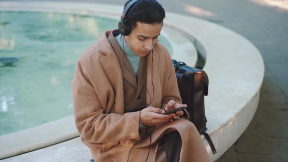 Overhead view of Arabian man texting by phone in headphones