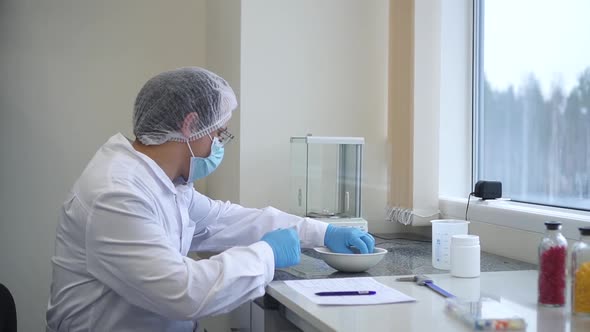 Worker in Sterile Rubber Gloves Weighs the Manufactured Tablets on the Control Scales