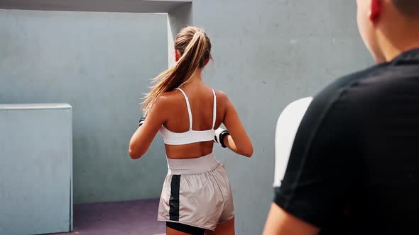 Boxing Training at the Construction Site Young Woman in White Top Kicking the Target in Her Coaches