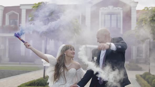 Caucasian Groom with Bride in the Park. Wedding Couple. Smoke Bombs. Newlyweds