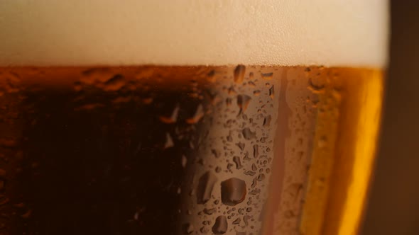 Detail Shot of Rotating Fresh Beer with Drops on Glass