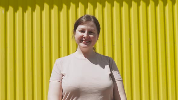 Simple Woman Without Makeup Smiling and Looking at Camera Near Yellow Wall